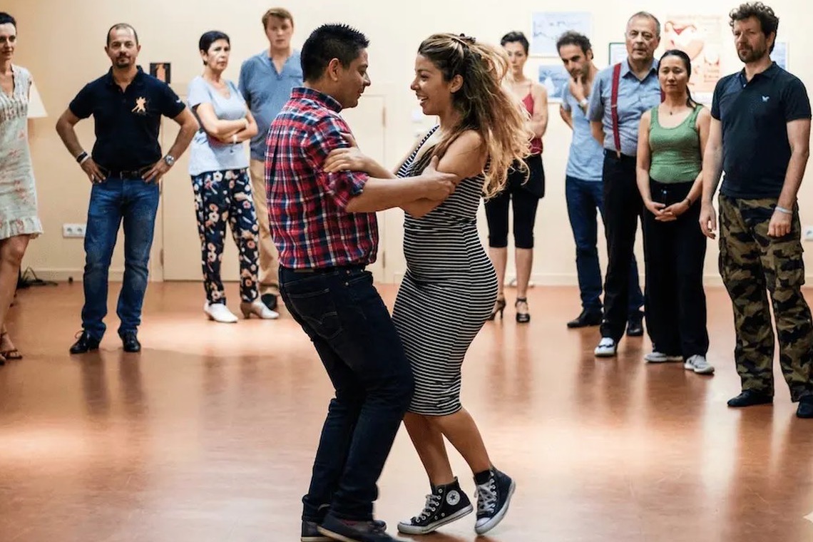 A tango class at BE-TANGO in Brussels: a couple dances while the group watches.
