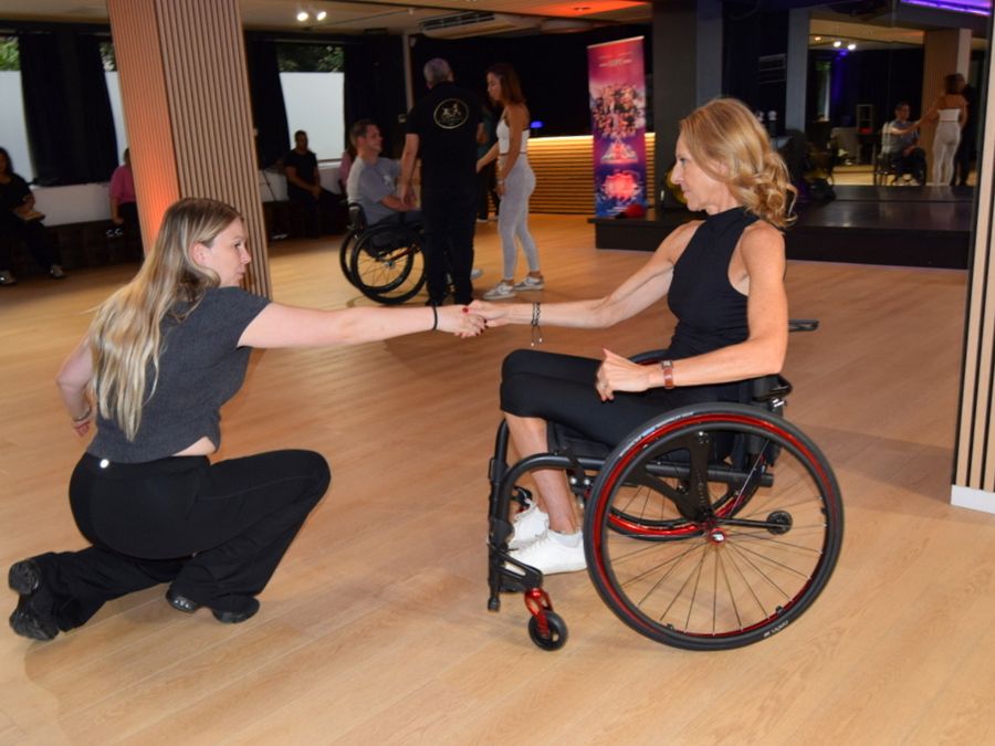 Two women dance together at the Studio 28 open day, one of them in a wheelchair.